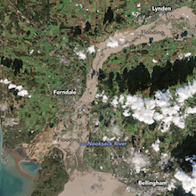 satellite image showing a muddy-colored flooded Nooksack River and surrounding towns including Ferndale and Bellingham