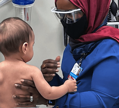 doctor in hijab holds and talks to baby