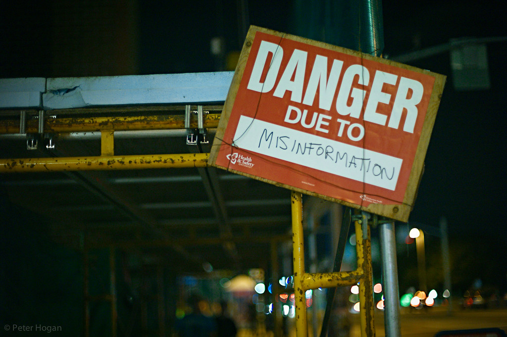 Construction site with a sign reading "DANGER due to MISINFORMATION"