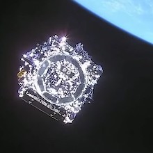 photo of a shiny square-ish object in orbit with earth in view